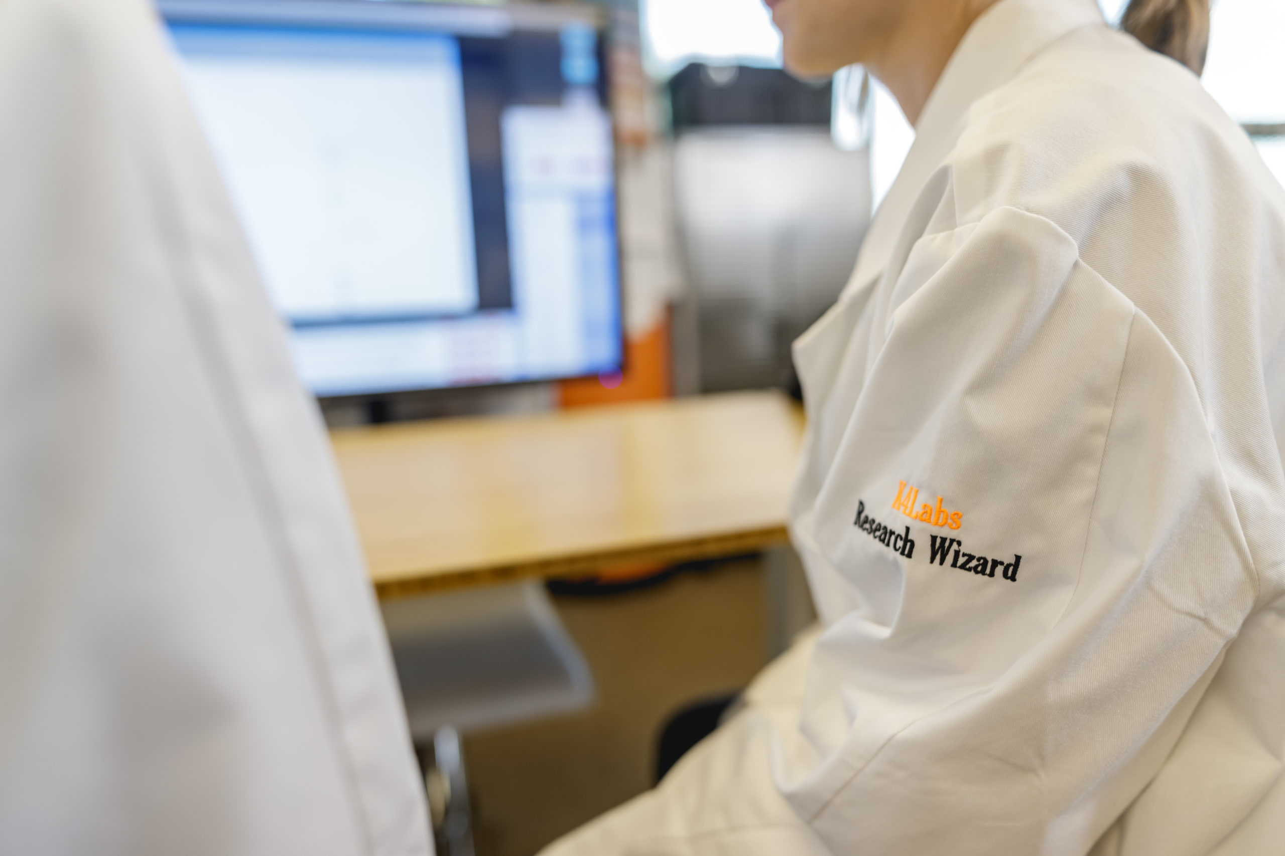 Two K4Labs team members discuss projects in Research Wizard branded lab coats